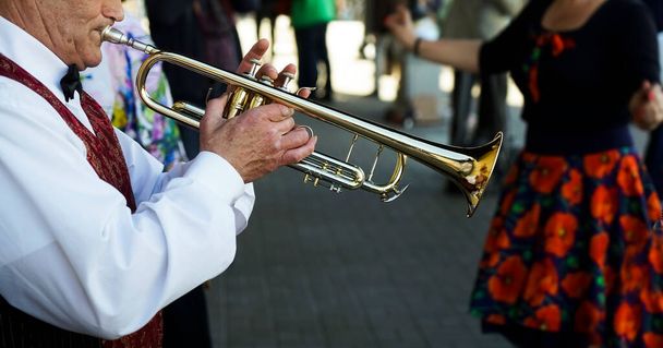 Saint Petersburg, Russian Federation - June 21, 2021: older man playing trumpet. Jazz Musician with Flugelhorn on street background.   - Zdjęcie, obraz