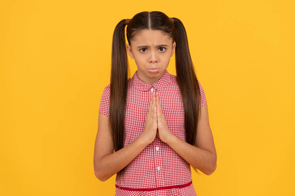 Unhappy girl prayer plead holding palms together in prayer gesture yellow background, pleading - Photo, Image