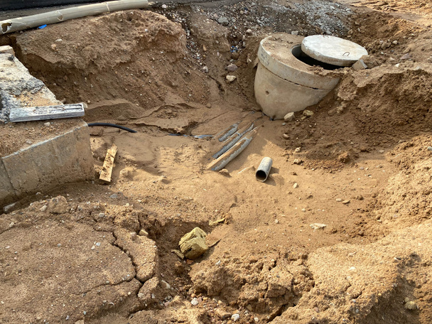 Бетонный люк в яме на строительной площадке. Промышленное строительство инженерных сетей канализации. - Фото, изображение