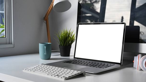 Moderno spazio di lavoro con computer mock up con schermo vuoto, tastiera, impianto e tazzina da caffè su tavolo bianco. - Foto, immagini