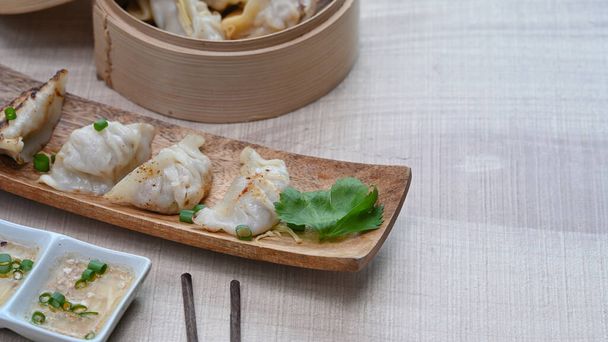Japanese gyoza, dumplings snack in rectangular wooden plate and chopsticks on wood table. - Φωτογραφία, εικόνα