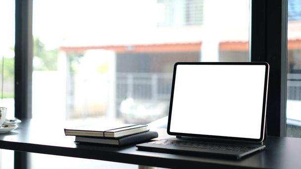 Werkruimte met mockup computer tablet en notebooks op zwart houten bureau. - Foto, afbeelding