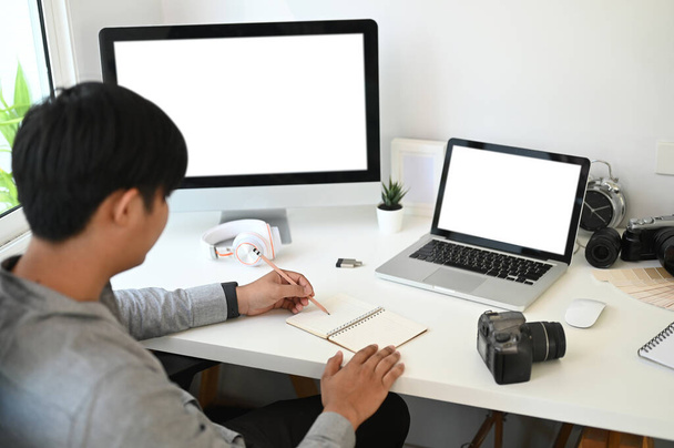 Grafický designér nebo fotograf bere na vědomí, když sedí před více počítači na pracovišti. - Fotografie, Obrázek