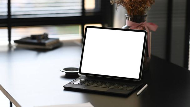 Vue de face d'une tablette d'ordinateur sur un espace de travail moderne et un écran vierge pour le montage d'affichage graphique. - Photo, image