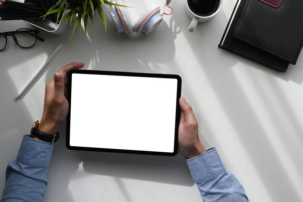 Κάτοψη ενός νέου δημιουργικού graphic designer hands κρατώντας ψηφιακό tablet σε λευκό τραπέζι. - Φωτογραφία, εικόνα