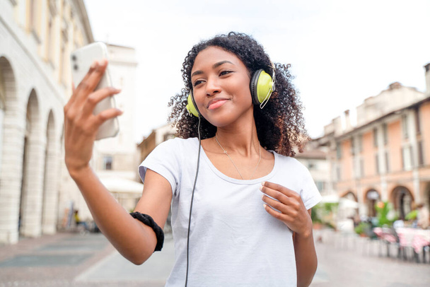 スマートフォンを使い路上で音楽を聴く少女 - 写真・画像