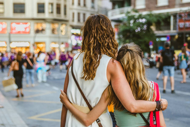 VALENCIA, SPAIN - Jun 30, 2021: View from behind of Mother and Daughter Embrace at Gay Pride march with Feminists in the Street in the Background - Foto, immagini