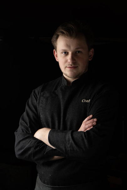Ritratto di un giovane chef in giacca su sfondo scuro - Foto, immagini