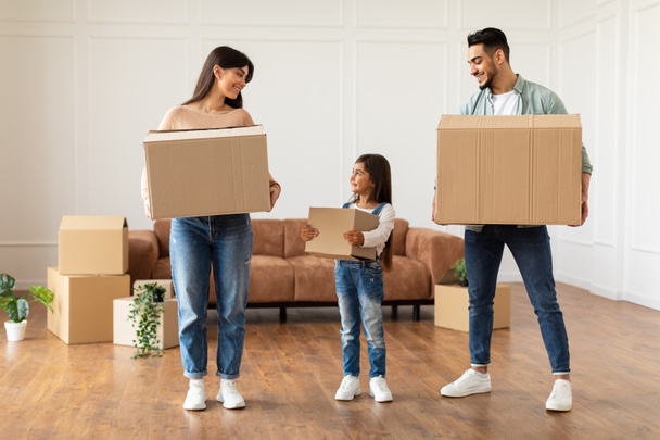 Счастливая молодая семья держит коробки в новой квартире - Фото, изображение