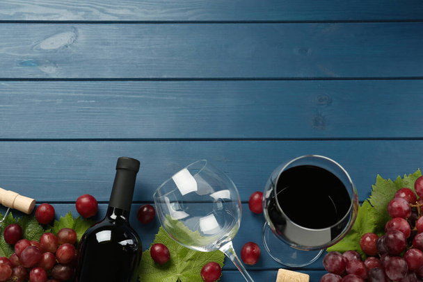 Tasty red wine and grapes on blue wooden table, flat lay. Space for text - Фото, зображення