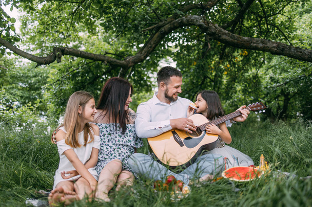Happy parents with two kids playing guitar on fresh air - Foto, Imagem