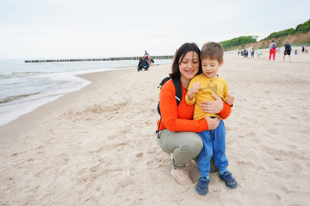TRZESACZ, POLAND - Jun 04, 2021: A woman and child standing on sandy beach - Photo, Image