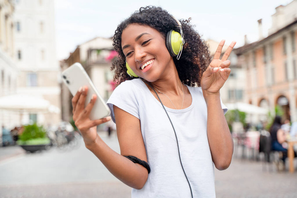 Happy young woman listening to music streaming in the city - Фото, зображення