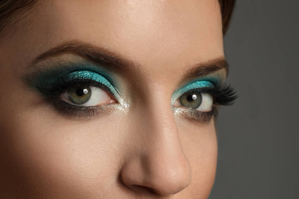 Young woman with evening makeup on grey background, closeup. Eye shadow product - Fotó, kép