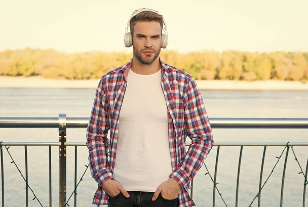 looking confident. quality of sound. innovative wireless device. unshaven guy with ear stereo headphones. male casual hipster fashion. man in headset listen song. music style. elearning concept - Фото, изображение