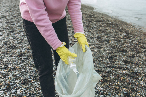 Bir kadın gönüllü kirli bir sahilde çöp topluyor.. - Fotoğraf, Görsel