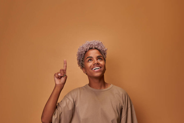African female makes gesture with index finger points upwards for advertisment - Fotó, kép