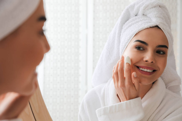 Woman using silkworm cocoon in skin care routine near mirror at home - Valokuva, kuva