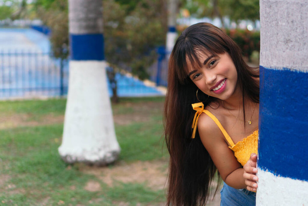 Νεαρό ισπανόφωνο κορίτσι χαμογελά ευτυχισμένοι με τα πόδια στο πάρκο. - Φωτογραφία, εικόνα
