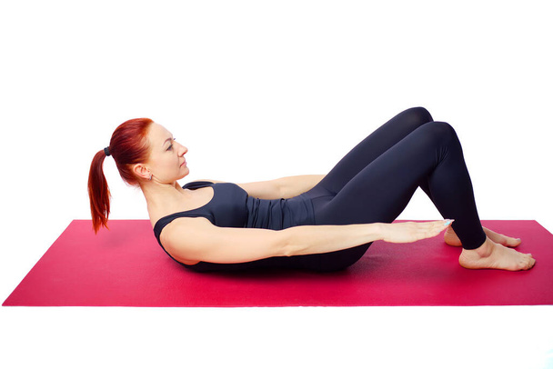 A beautiful slender woman performs an exercise to develop the strength of the abdominal muscles on a gym mat.  - Photo, Image