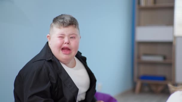 Weinendes Kind mit Down-Syndrom ist aufgebracht wegen einer fehlerhaften Aufgabe oder Schwierigkeiten bei der sozialen Anpassung im Klassenzimmer - Filmmaterial, Video