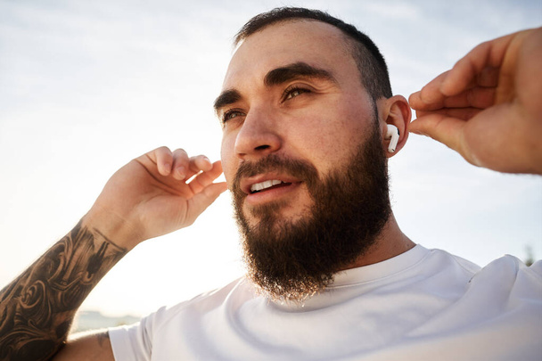 Close up of a man athlete listening to music while having a walk in countryside - Foto, Imagen