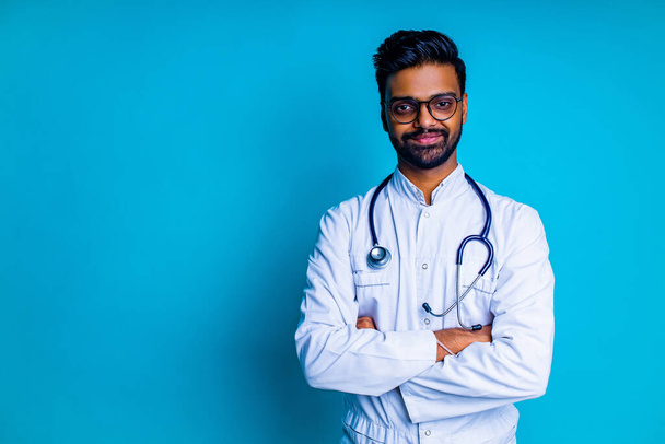 young latin hispanic medican man wear eye glasses with stethoscope in blue studio wall background - Foto, imagen