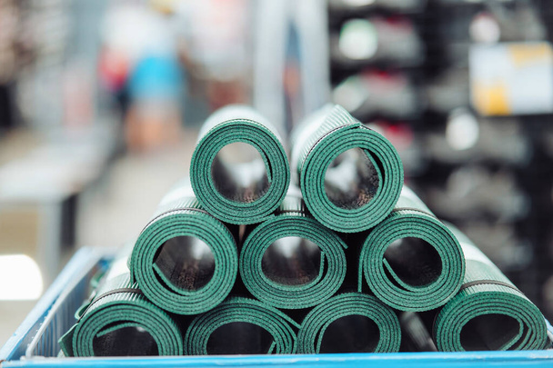 Новые свернутые коврики для йоги и фитнеса на полке магазина. Close view. - Фото, изображение