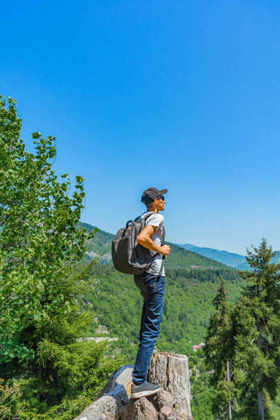Ο νεαρός κοιτάζει την απόσταση στα πράσινα βουνά. Backpacker άνθρωπος κοιτάζοντας προς την εξωτερική απόσταση. - Φωτογραφία, εικόνα