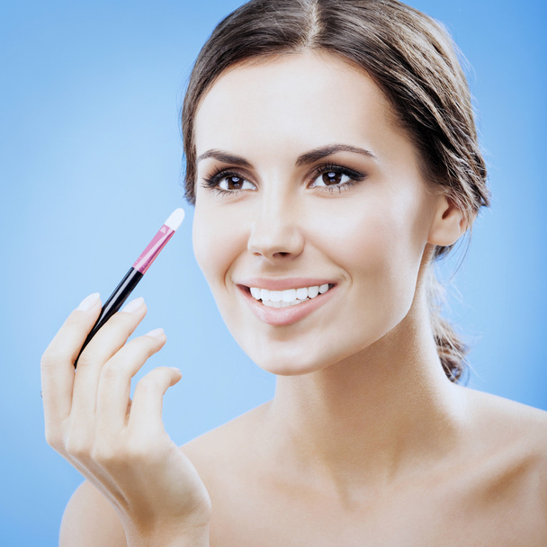 Woman with cosmetics brush, on blue - Foto, afbeelding