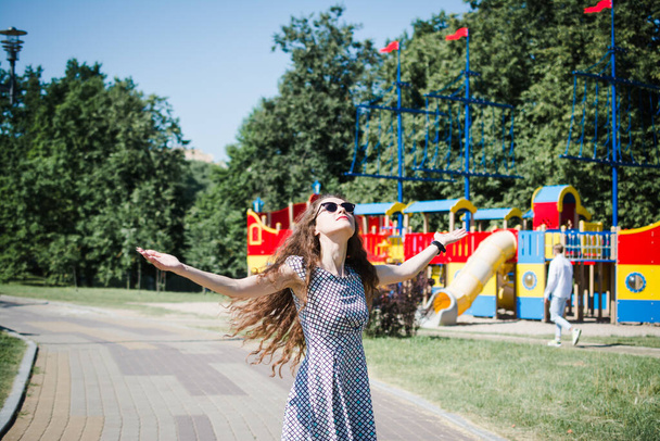 A beautiful Russian girl walks in the city park in the summer and rejoices - Photo, image