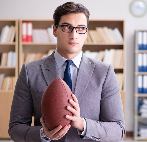 Бизнесмен с американским футболом в офисе - Фото, изображение