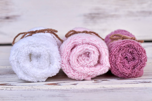 Trzy kolorowe rolki ręcznika na białym drewnianym tle. - Zdjęcie, obraz
