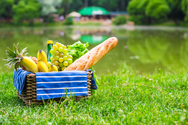Cesta de picnic con frutas, pan y botella de vino blanco
 - Foto, imagen