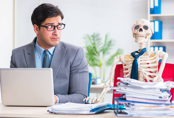 Бізнесмен, що працює зі скелетом в офісі
 - Фото, зображення