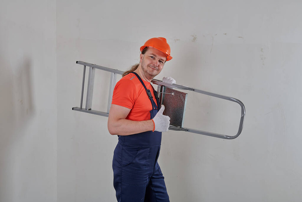 um engenheiro usando um capacete laranja segura uma escada rolante - Foto, Imagem