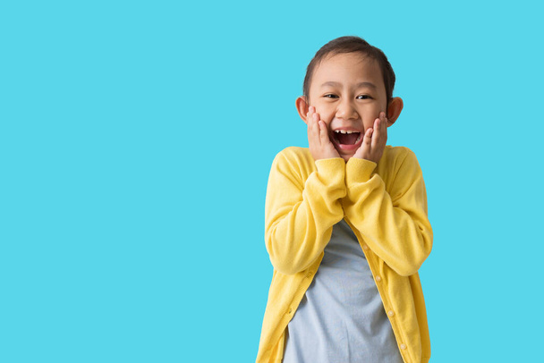 Happy asian child girl of surprised cute with hands near open mouth,  isolated over blue background - Foto, Imagen