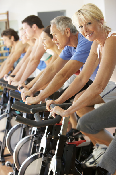 Senior Woman Cycling In Spinning Class In Gym - Photo, Image