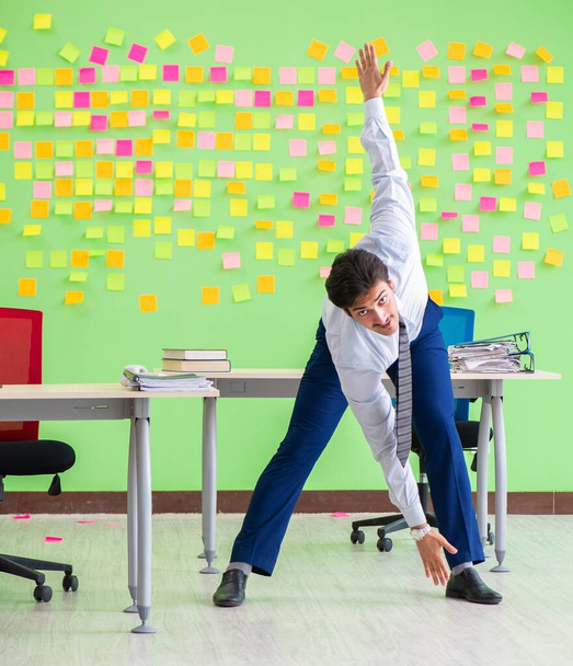 Человек в офисе со многими противоречивыми приоритетами делает упражнения - Фото, изображение