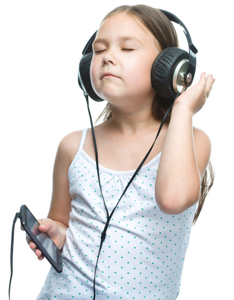 μικρό κορίτσι απολαμβάνει τη μουσική χρησιμοποιώντας ακουστικά - Φωτογραφία, εικόνα