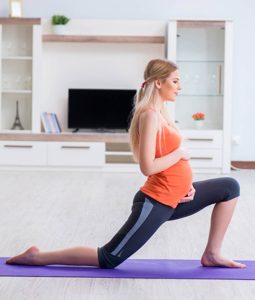 Pregnant woman doing sport exercise at home - Foto, Imagen