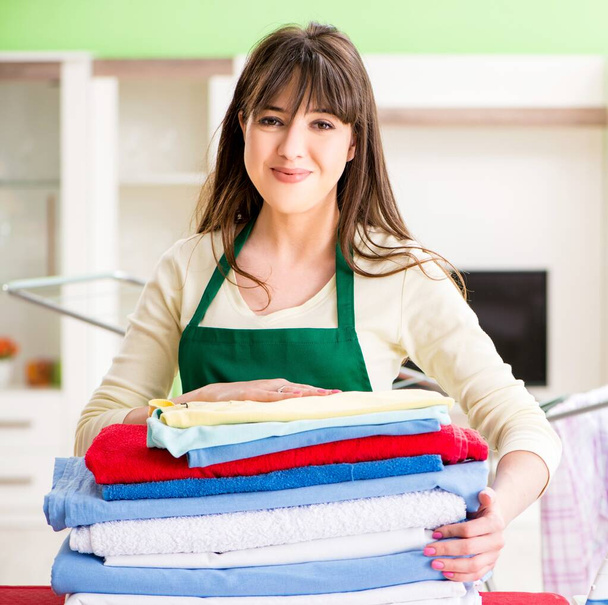 Mujer joven planchando ropa en casa - Foto, imagen