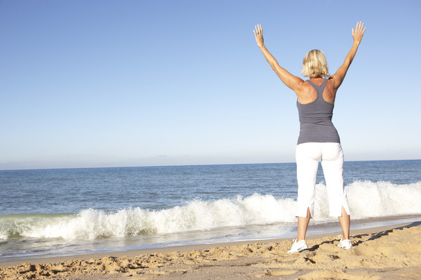 Senior Woman In Fitness Clothing Stretching On Beach - Fotó, kép