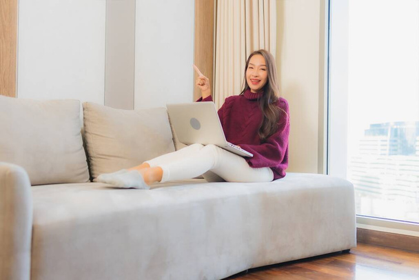 Portrét krásná mladá asijská žena použít počítač notebook na pohovce v obývacím pokoji interiéru - Fotografie, Obrázek