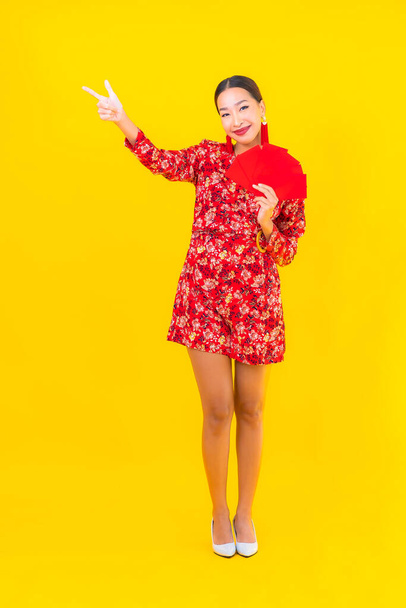 Retrato hermosa joven asiática mujer con sobres rojos sobre fondo amarillo - Foto, Imagen