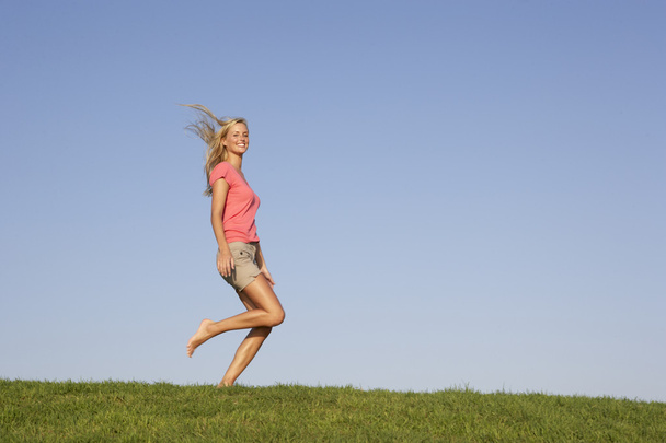 Young woman running through field - 写真・画像