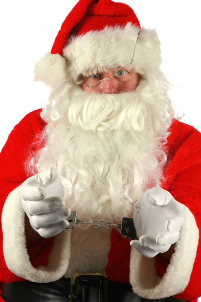 Lustige Weihnachten. Der Weihnachtsmann wird verhaftet. Weihnachtsmannbecher Schuss vorhanden. Der Weihnachtsmann lässt sich für seine Tasse Shot fotografieren, während er Handschellen trägt. Der Weihnachtsmann war in diesem Jahr schlecht. Schlechter Weihnachtsmann. Weihnachtsmannbecher Schuss vorhanden. Weihnachtsmann Weihnachten. Der Weihnachtsmann wird verhaftet. isoliert. - Foto, Bild