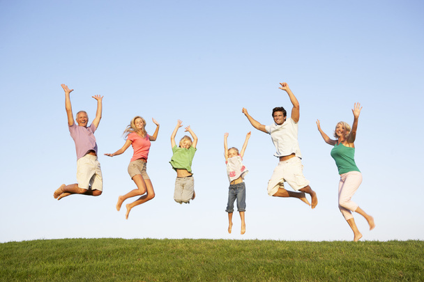 Young couple with grandparents and children jump in a field - Foto, Imagem