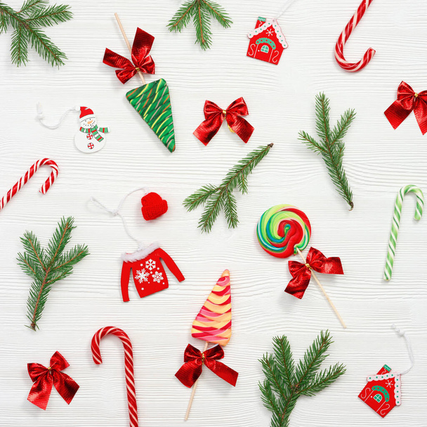 Christmas composition. Christmas sweets and candy canes, pine branches, and New Year wooden toys on white table, top view, flat lay. - Photo, Image
