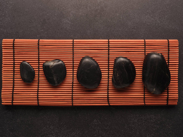 Five hot stones massage stones on a bamboo mat, health care, aromatherapy, header or backdrop - Foto, immagini